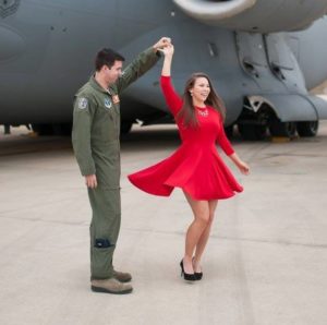 engagement photo twill man in pilots jumpsuit twirling girl in red dress